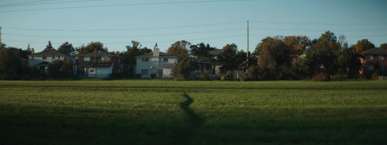 A landscape view of a field behind houses in a neighborhood