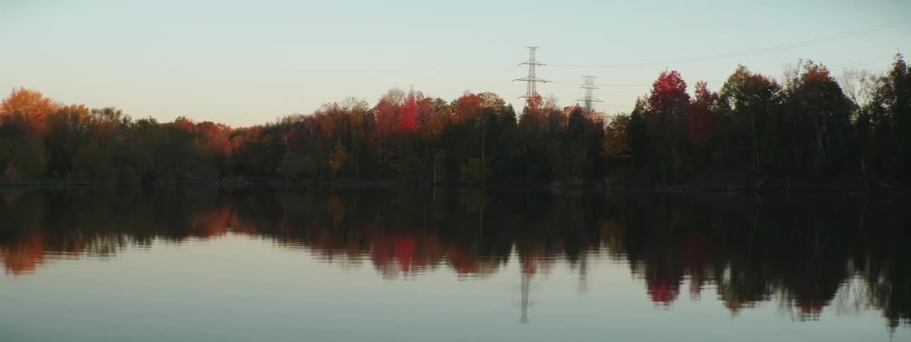 Rippling water reflects transmission towersand trees with their fall foliage