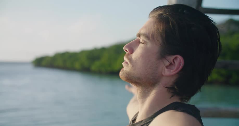 A man does yoga as he sits near a body of water
