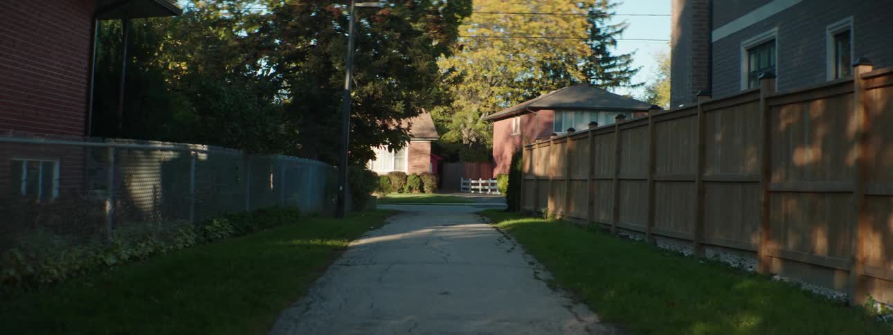 One lane alley leads between building toward road