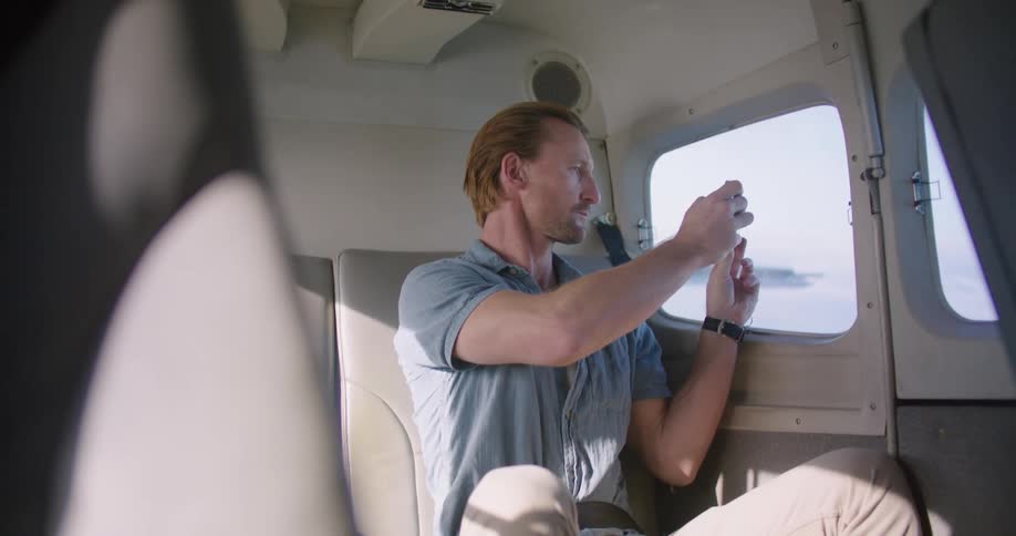 A man is sitting in the cabin of a vehicle as he looks out a window and takes pictures
