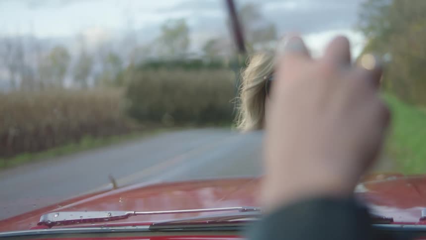 A woman putting on glasses in a car