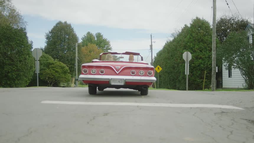 Man and woman drive off in convertible with its top down and a personalized license plate