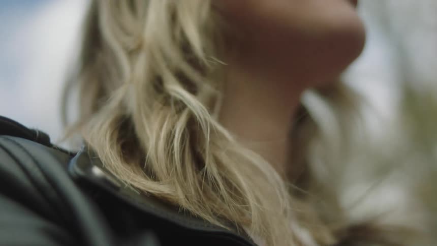 Blonde woman with black leather jacket drives car with folding roof