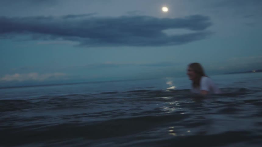 A man and woman play fighting in the ocean