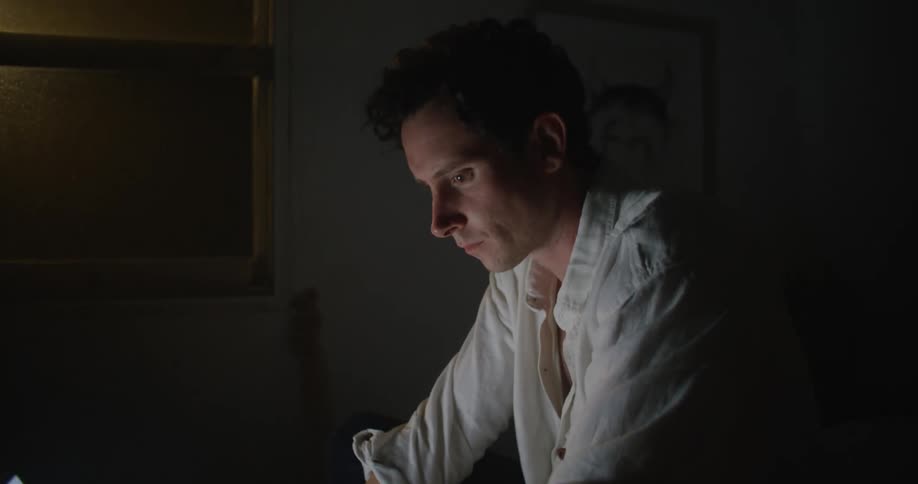 A man sitting in a room typing on a laptop