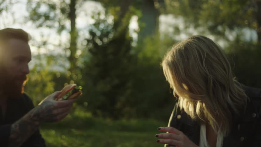 A man and woman eating food sitting outside