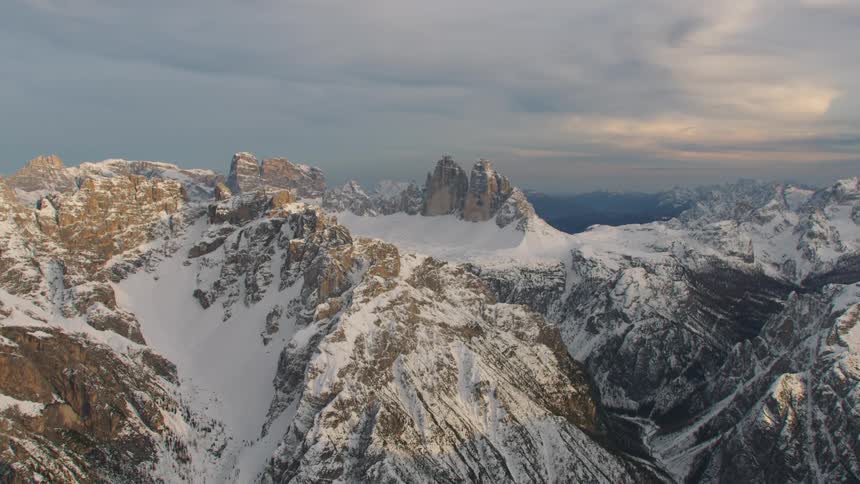 An aerial view of a snowy mountain landscape on an overcast day