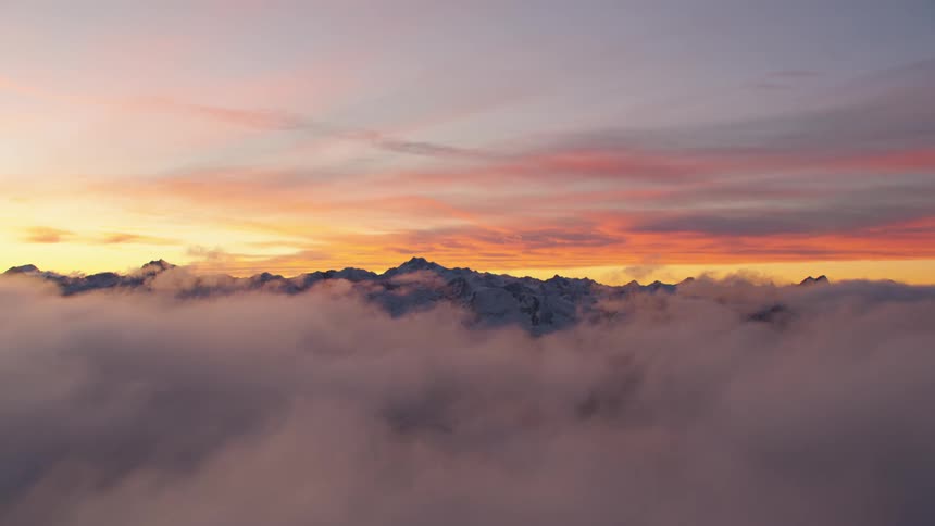 Thick clouds dissipate to reveal a snow covered mountain