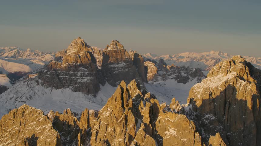 Sun casts shadows across snowy mountains under clear sky