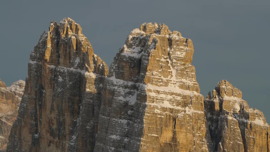 Snow around the edges of rock formations high in a clear sky