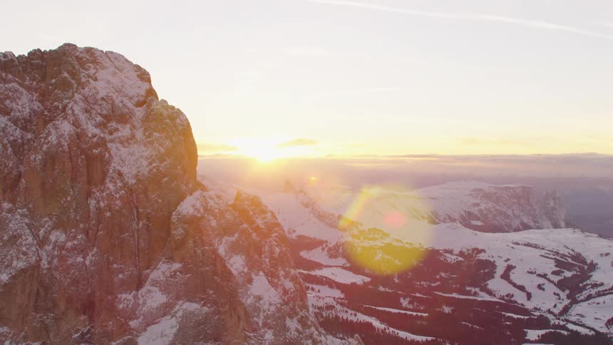 Giant rock crags are partially covered in snow in the mountain wilderness at sunrise