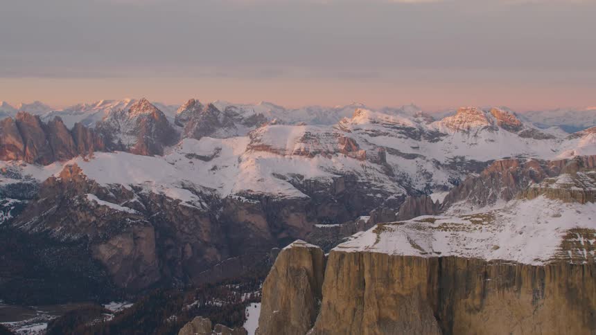 The sunlight hits the tops of snow dusted mountain ridges