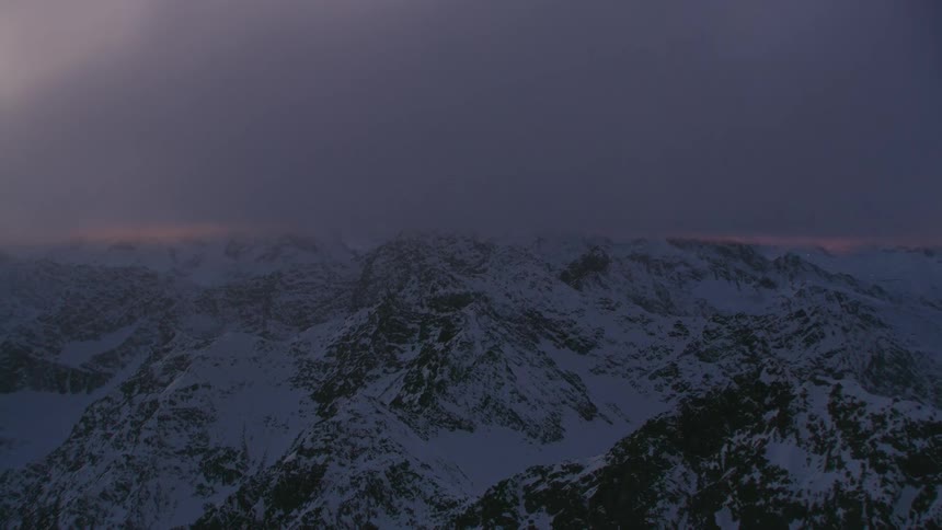 Moving under the cloud layer to see the golden sunrise over snowy mountain ridges and peaks