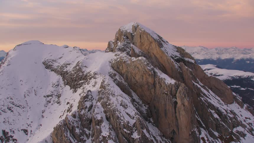 An aerial view of a snow covered mountain range as the sun sets