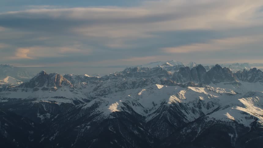 Snow covered mountain range with peaks high in a cloudy sky