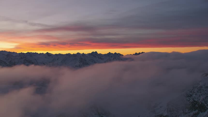 Mountains peek through in the distance between two layers of storm clouds