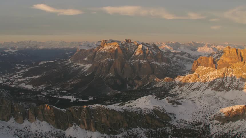 Sunlight shines on a rocky ridge creating a golden glow above shadow and snow