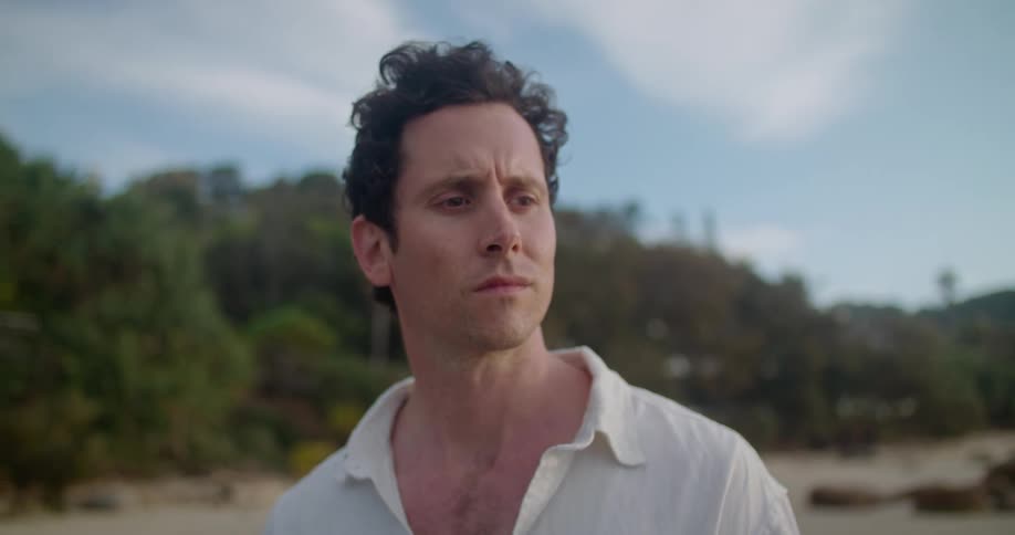 A man standing on the sand looking out with a furrowed brow