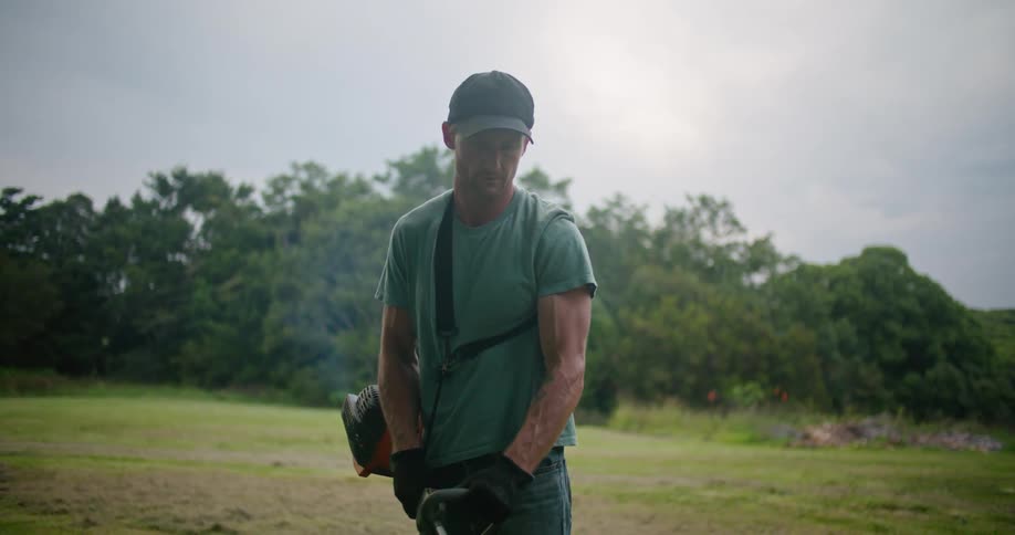 A man is cutting the grass with a trimmer