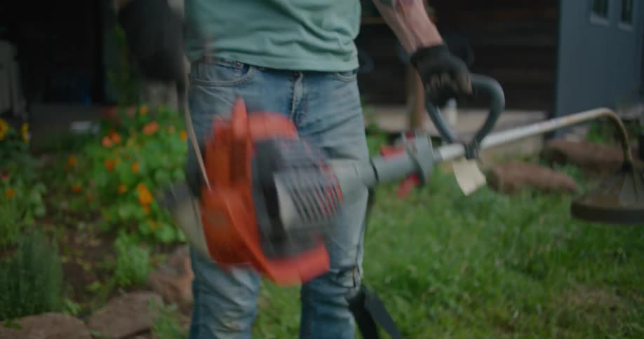 Man stands in yard priming and attempting to start gas powered grass trimmer