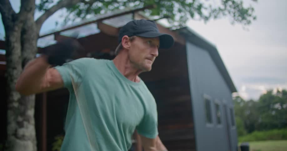 A man gets frustrated as he pulls and pulls on a cord on his lawn equipment that is not starting