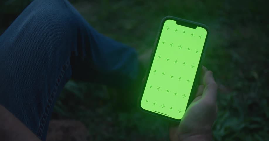 A smartphone screen glows at dusk while a mans thumb scrolls and taps