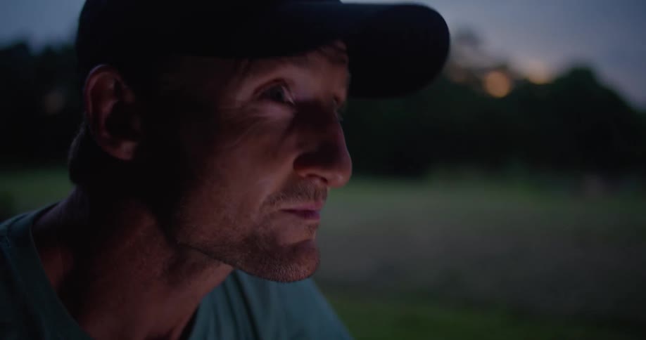 Man sits on ground in field scrolling on mobile phone