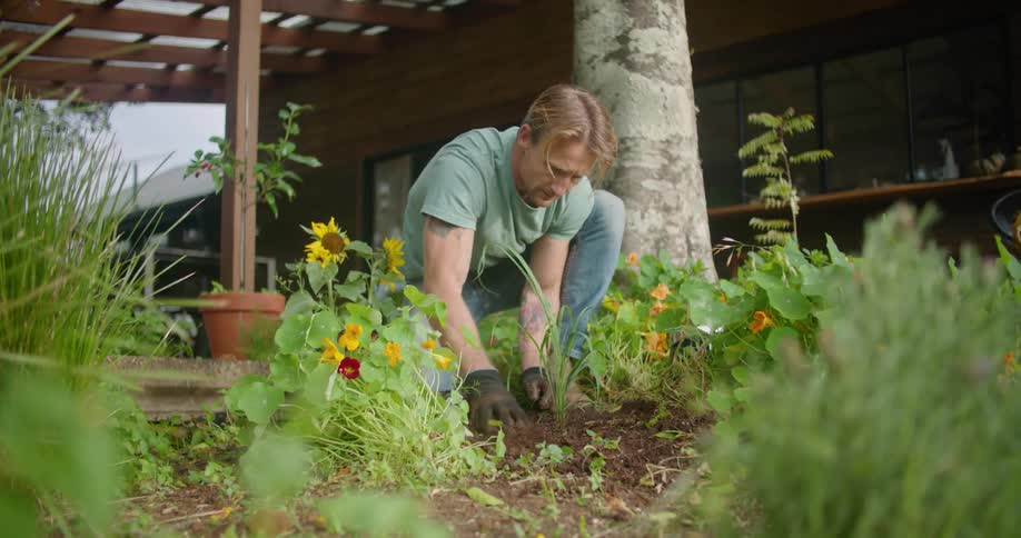 A man is working in a flower bed at a house