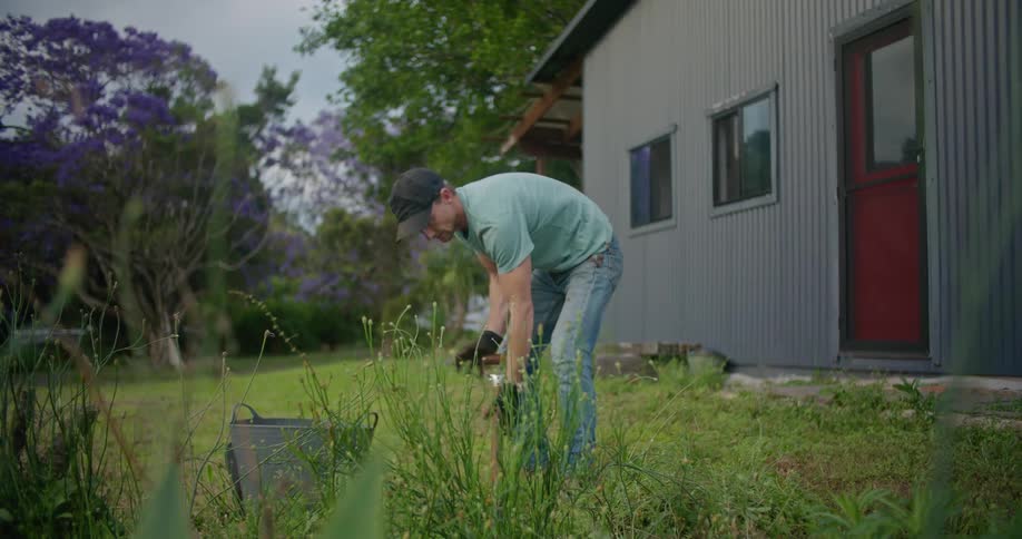 Man digs into ground in house yard and places dirt into bucket