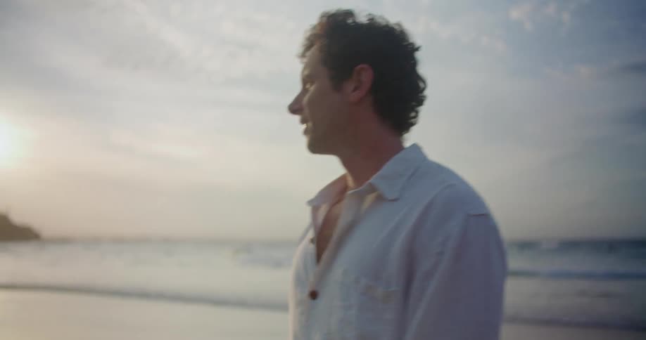 A man standing on a beach looks up closing his eyes in contentment