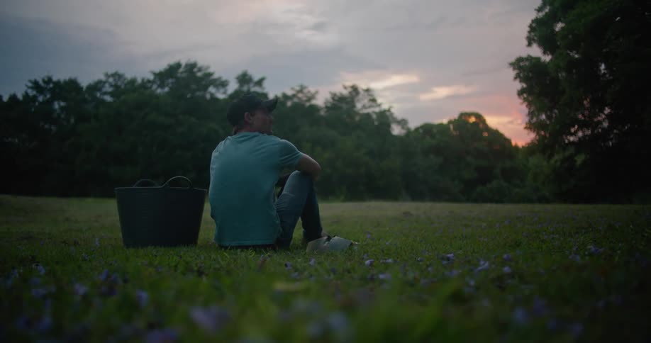 A man sits next to a bucket on the field