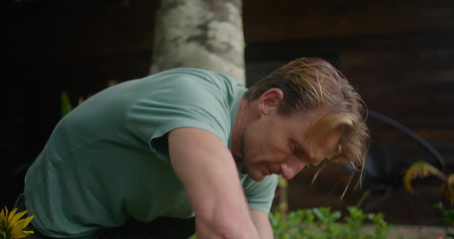 A man is digging a hole in a garden with a hand trowel
