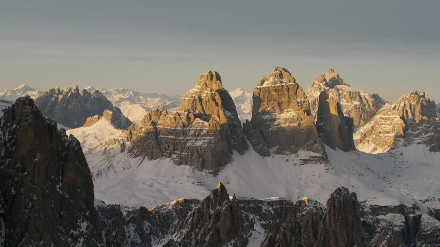 An aerial view of a snowy rocky mountain landscape in the daytime