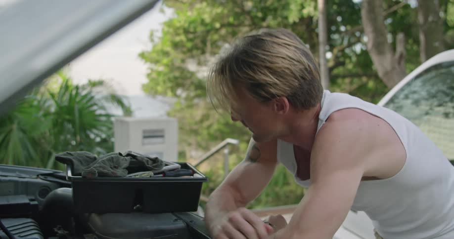 A frustrated mechanic working on a car