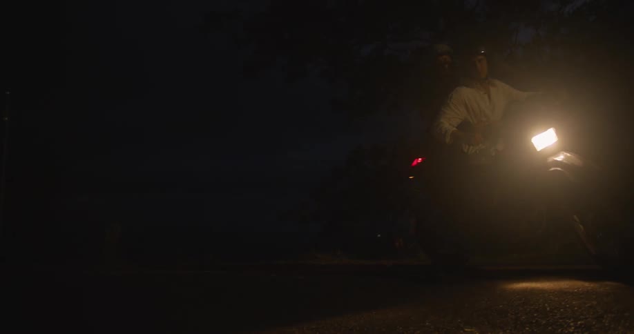 Young couple riding a motorcycle on a road at night