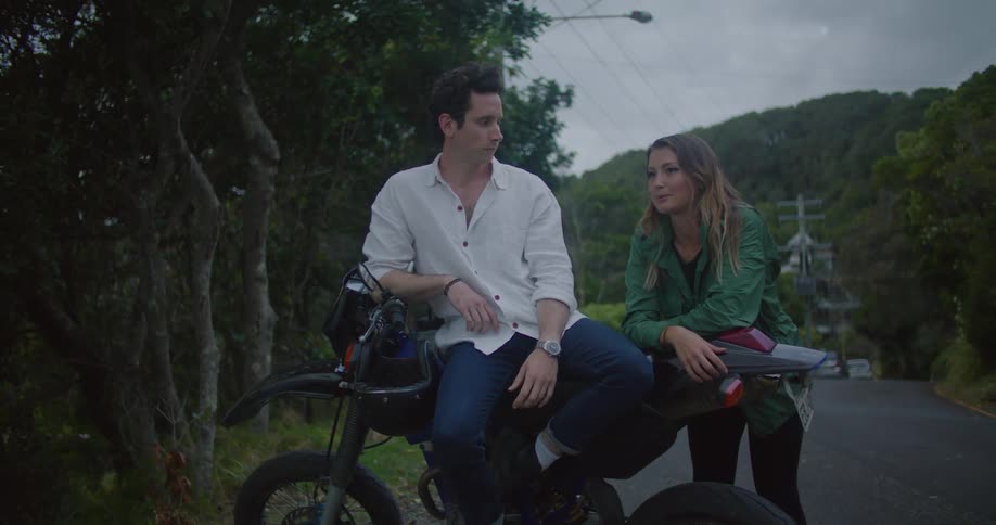 A man and woman rest on their motorbike on the side of the road