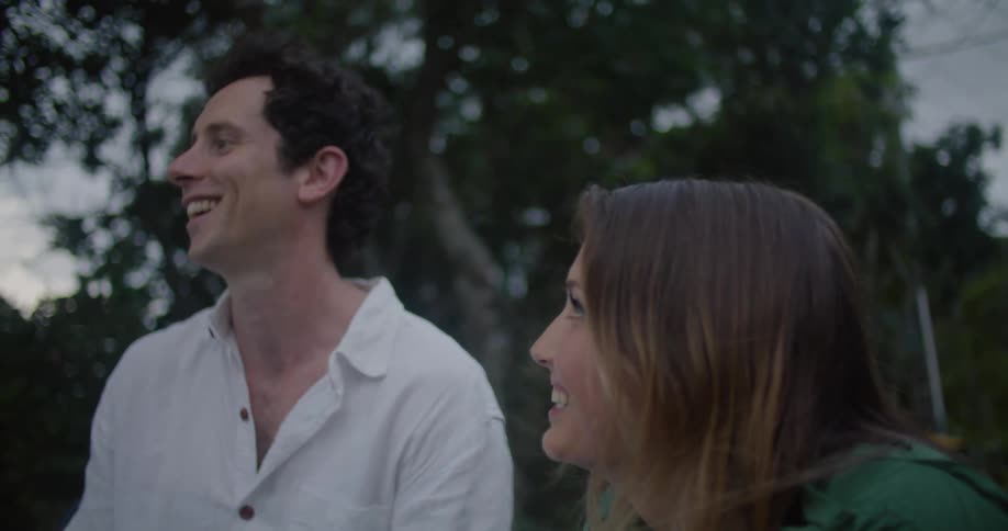 A man and a woman are having casual conversation while outdoors on a cloudy day