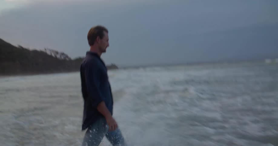 A man walks into the ocean fully dressed