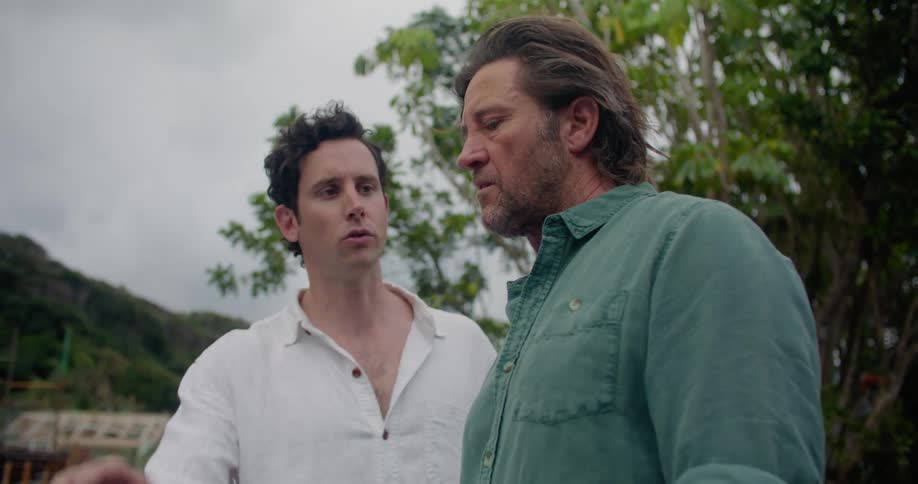Two men are discussing construction plans using a laptop while standing outdoors in a neighborhood on a mountain