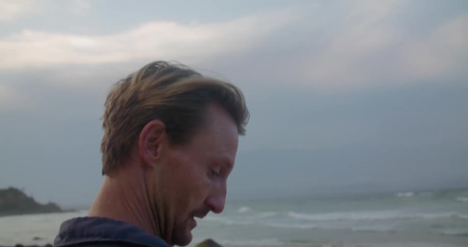 A man is standing on a beach watching the waves roll in