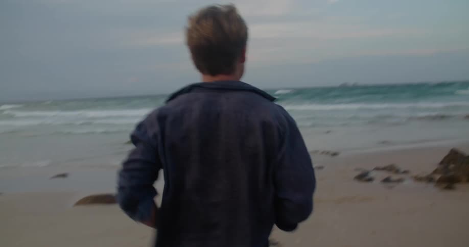 A man runs towards the waves on the beach