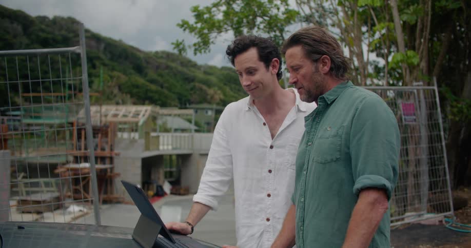 Two men are talking during a zoom meeting on a laptop at a building construction site