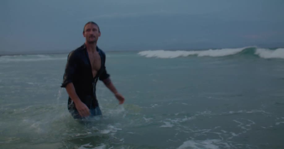 A man swimming out in the ocean in his clothes