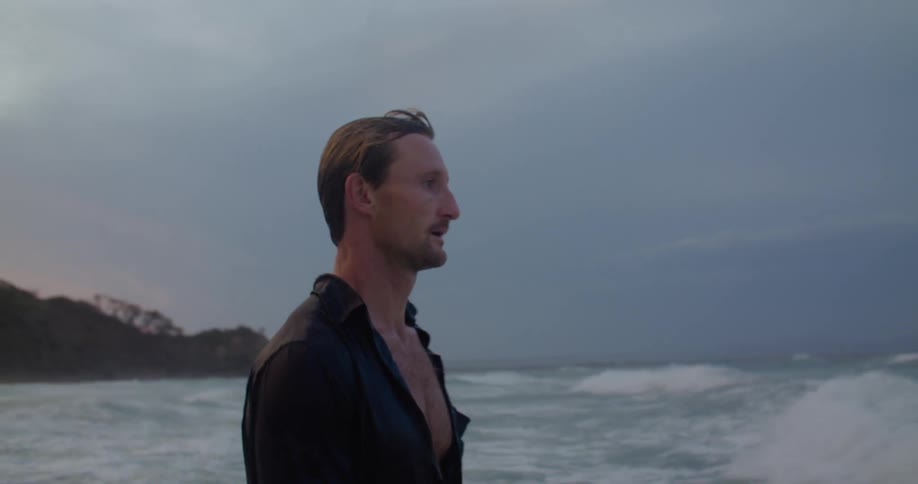 Man wearingpants and a shirt turns and lets himself falling surf