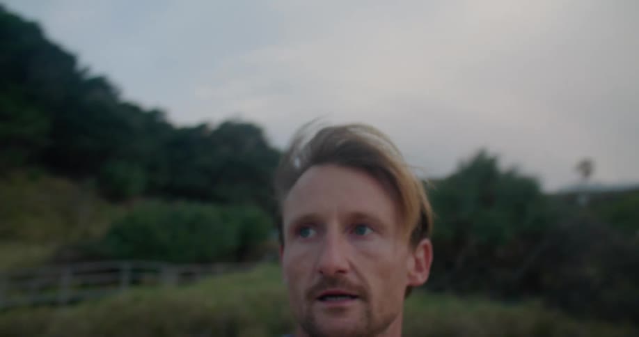 A man looks scared as he stops then runs again on a beach