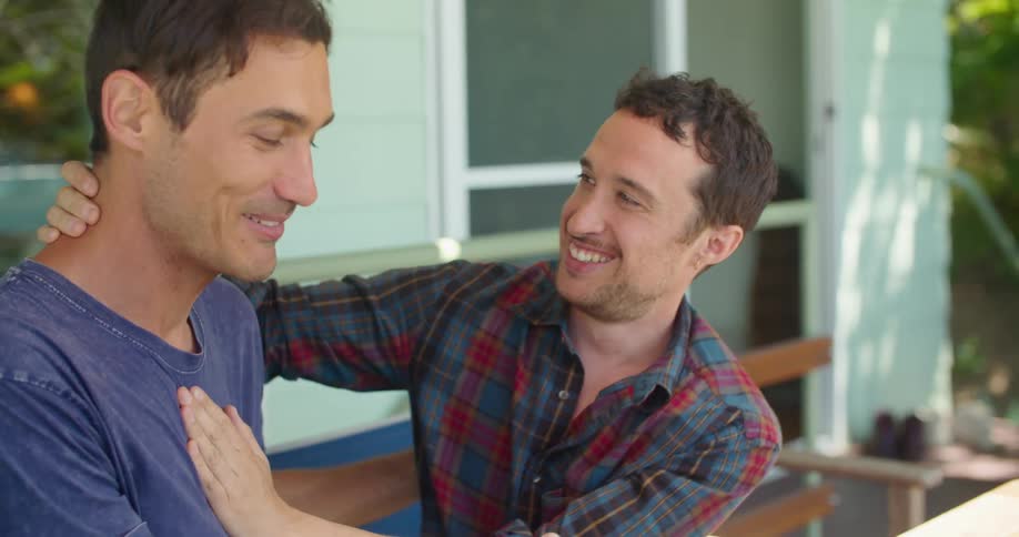 A man kisses his partner on the cheek before they eat outside
