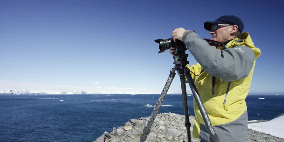 A man takes photographs near the water