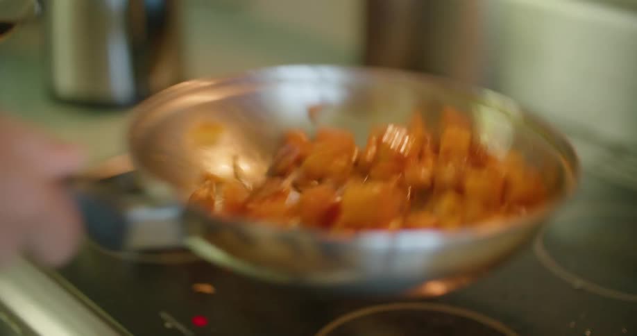 A person flips food in the pan while cooking