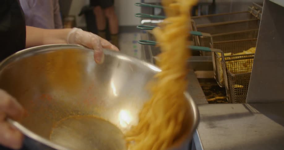 A woman is preparing french fries in a restaurant in the daytime